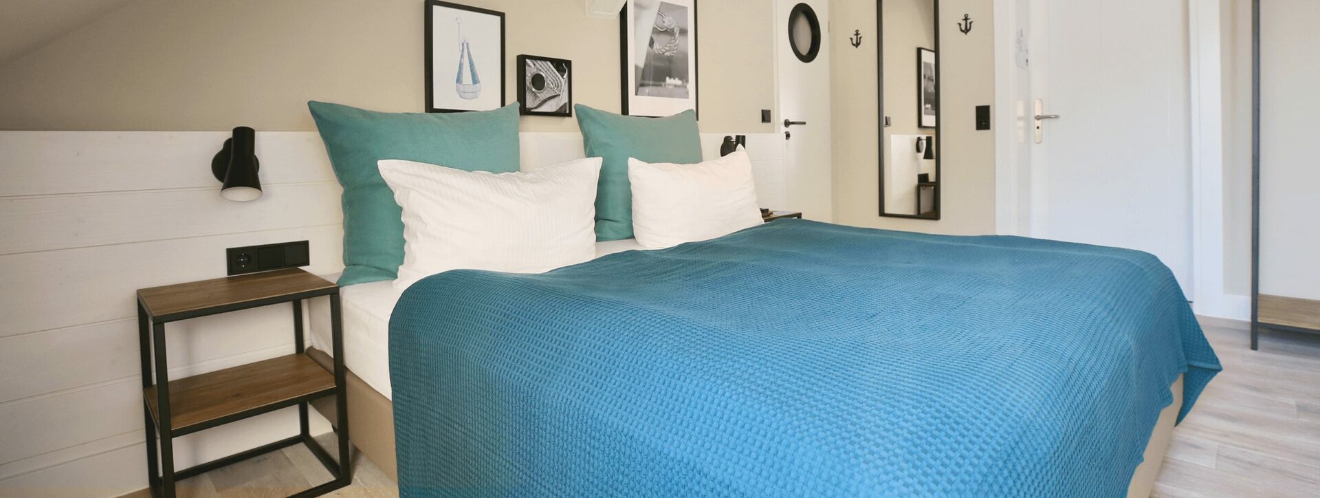Längliches Foto von einem Hotelzimmer in Heringsdorf mit Doppelbett, Nachttischen, Bildern und separatem Badezimmer