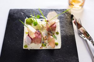 Nahaufnahme eines Gerichts, das in einem Restaurant in Heringsdorf auf einer Schieferplatte kunstvoll angerichtet ist