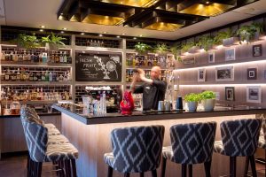Foto einer Bar in einem Hotel in Heringsdorf, auf dem der Barkeeper gerade einen Cocktail mixt