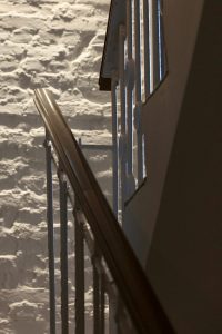 Nahaufnahme von einem Treppengeländer, das sich vor einer steinernen Wand in einem Boutique Hotel auf Usedom befindet