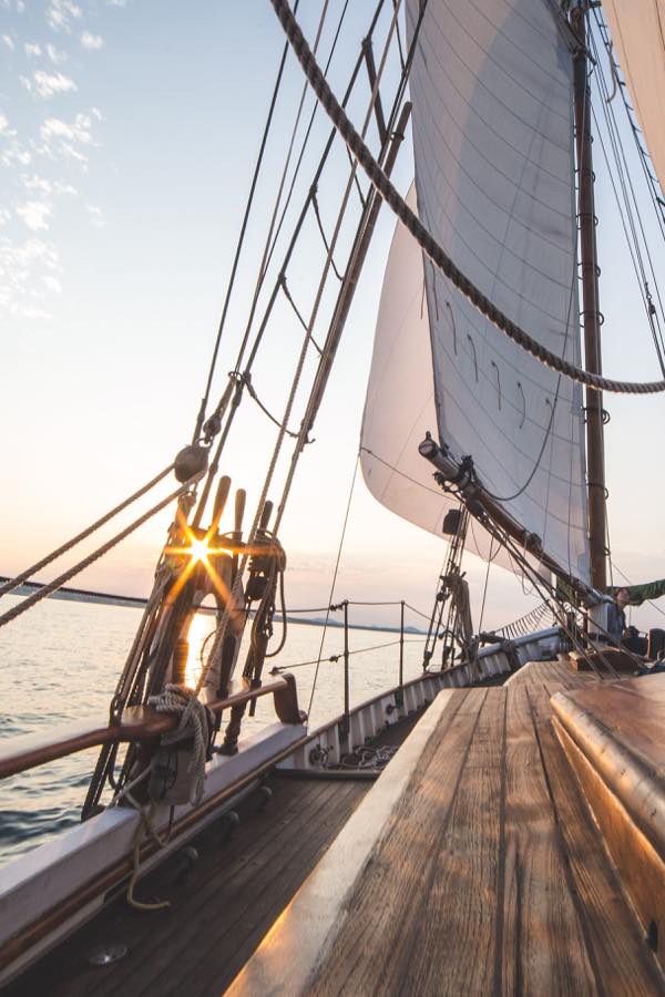 Ein hölzernes Segelboot, welches bei untergehender Sonne auf Land zusegelt und als Motiv häufig auch im Boutique Hotel auf Usedom, der BOJE06 zu finden ist