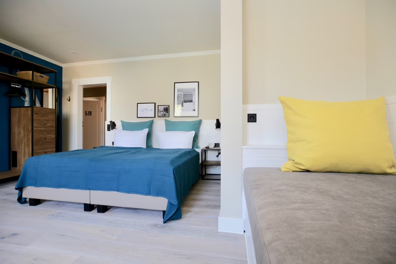 Foto eines geräumigen Hotelzimmers in Heringsdorf mit Doppelbett, Schlafsofa, einer Garderobe sowie angrenzendem Badezimmer