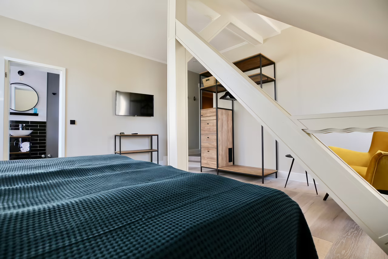 Foto von einem Hotelzimmer in Heringsdorf mit Doppelbett, Sitzecke, Garderobe, TV und angrenzendem Badezimmer