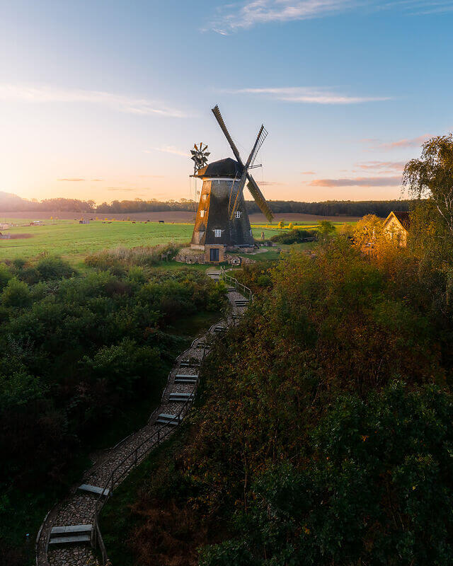 Eine freistehende Windmühle in sommerlicher Landschaft, Treppen führen zu ihr hinauf